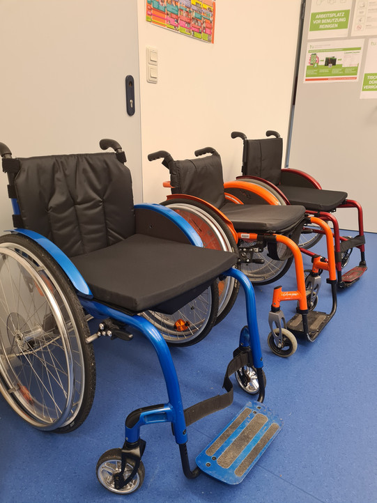 Drei manuelle Rollstühle stehen nebeneinander.