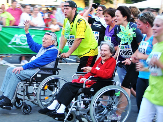 Ein Marathon. Es sind laufende Menschen und Menschen in Rollstühlen zu sehen.